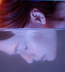 A red-headed woman, her eyes closed, and face submerged in water. You Are Awesome.